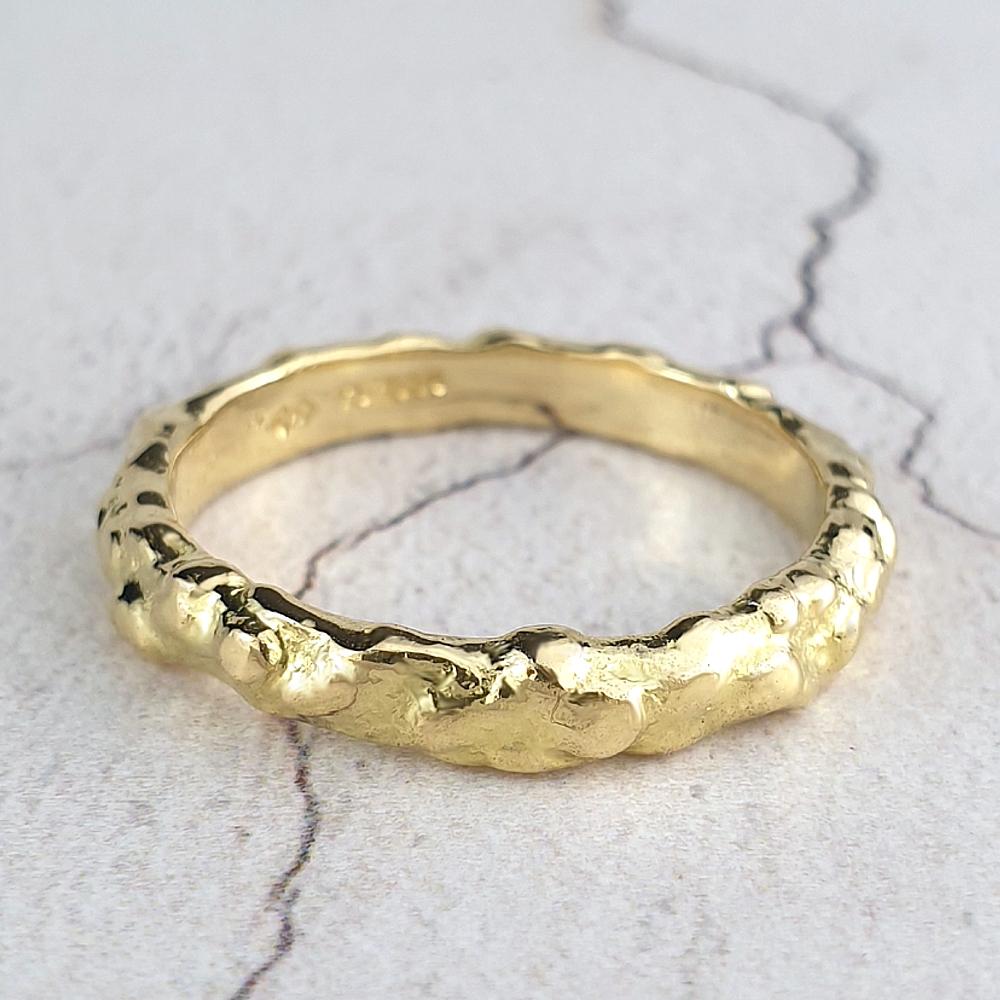 A narrow band of 18ct yellow gold with a nugget-texture