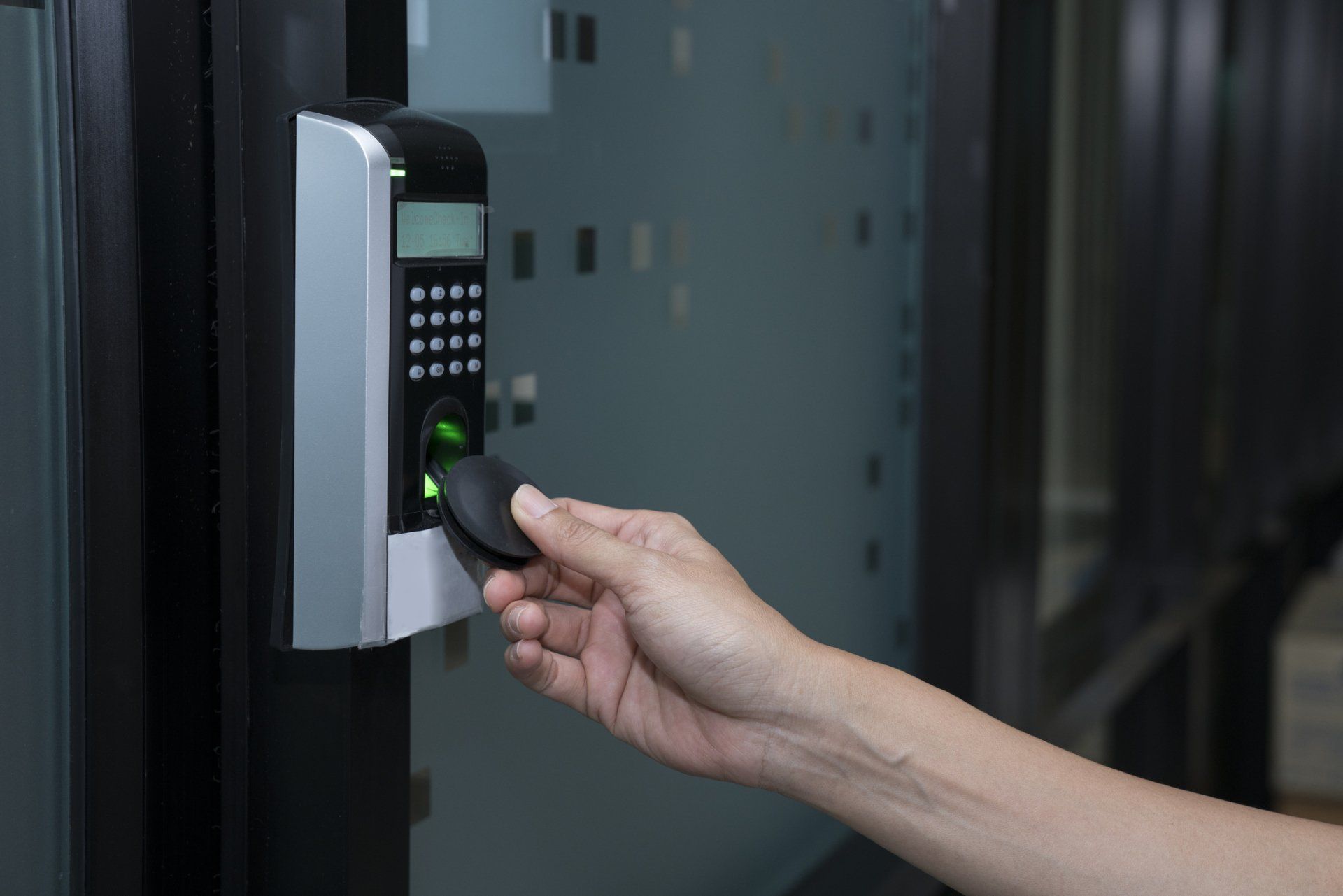 Hand scanning a fingerprint reader on a door access control panel
