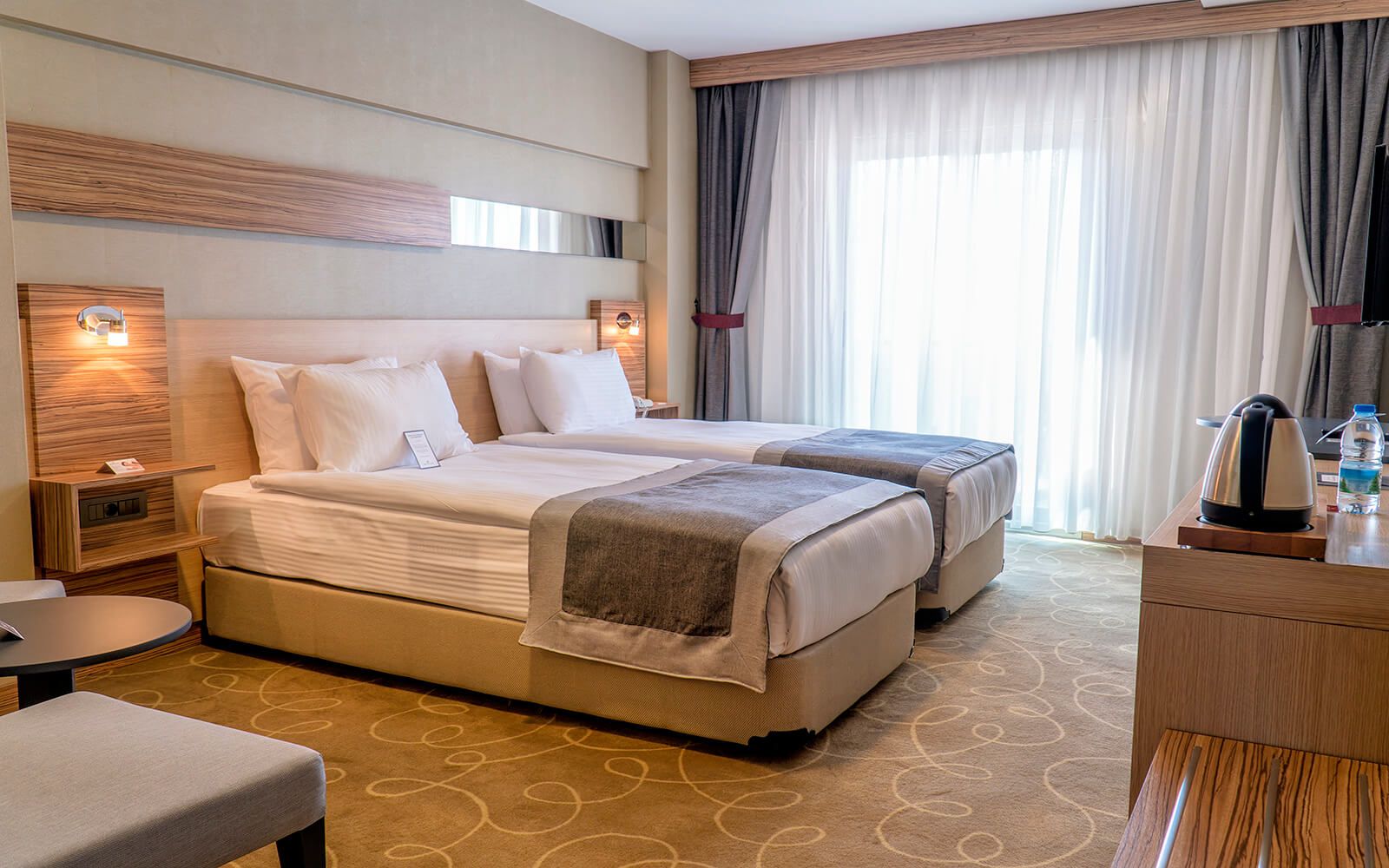 Iki yataklı ve geniş pencereli bir otel odası.