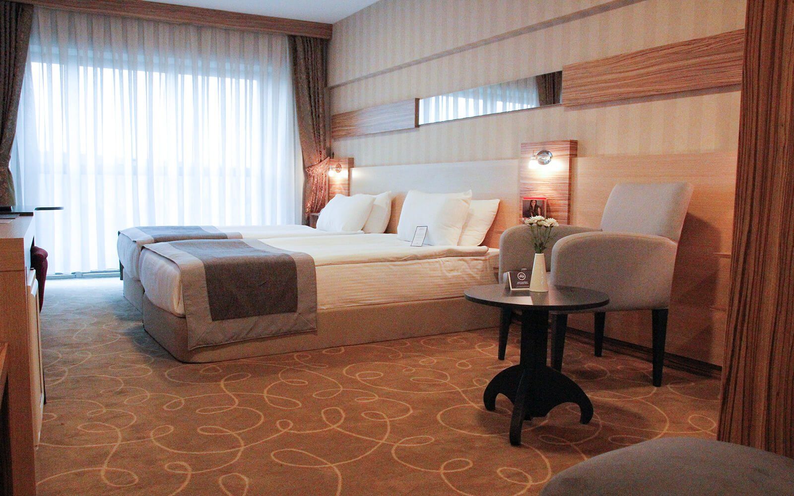 Iki yatak, bir sandalye ve bir masadan oluşan bir otel odası.