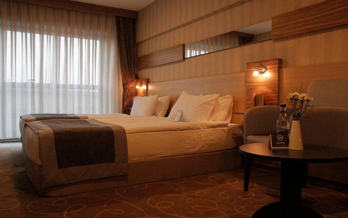 Içinde yatak, sandalye, masa ve pencere bulunan bir otel odası.