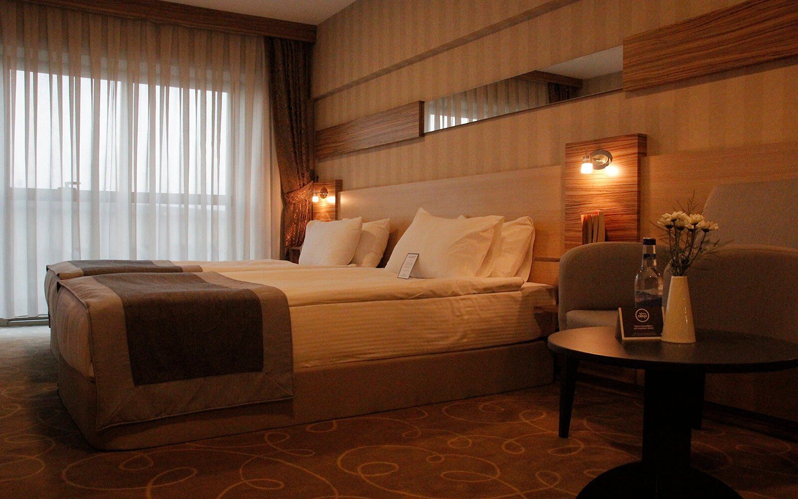 Içinde yatak, sandalye, masa ve pencere bulunan bir otel odası.