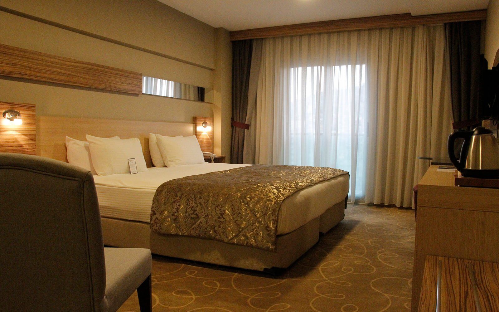 Iki yataklı, bir sandalyeli ve televizyonlu bir otel odası.