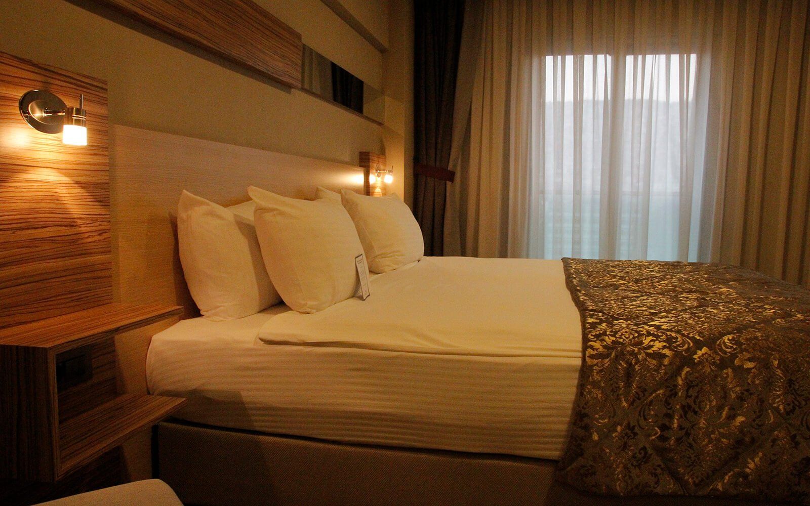 Büyük bir yatağı ve penceresi olan bir otel odası.