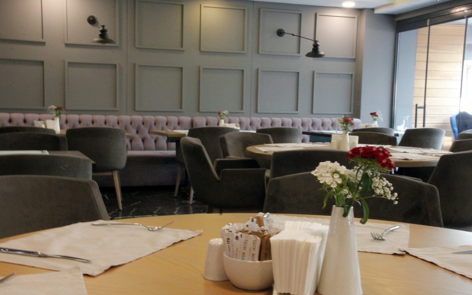 Masaları, sandalyeleri ve masanın üzerinde çiçeklerle dolu bir vazosu olan bir restoran.