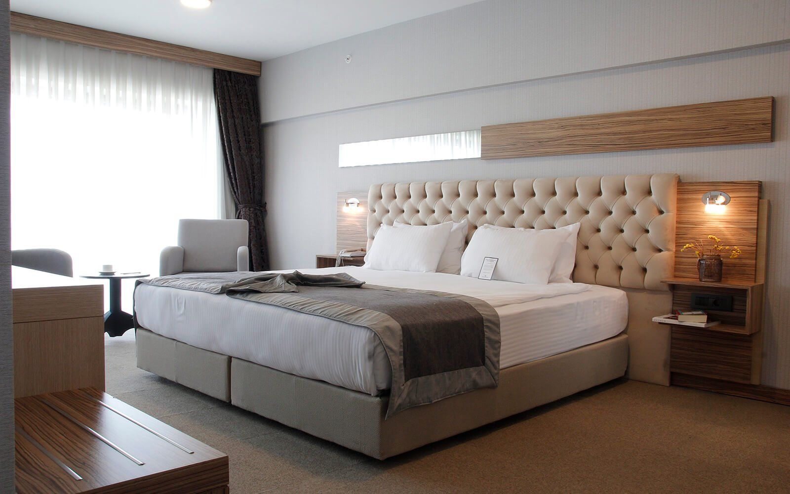 Kral yataklı ve sandalyeli bir otel odası.