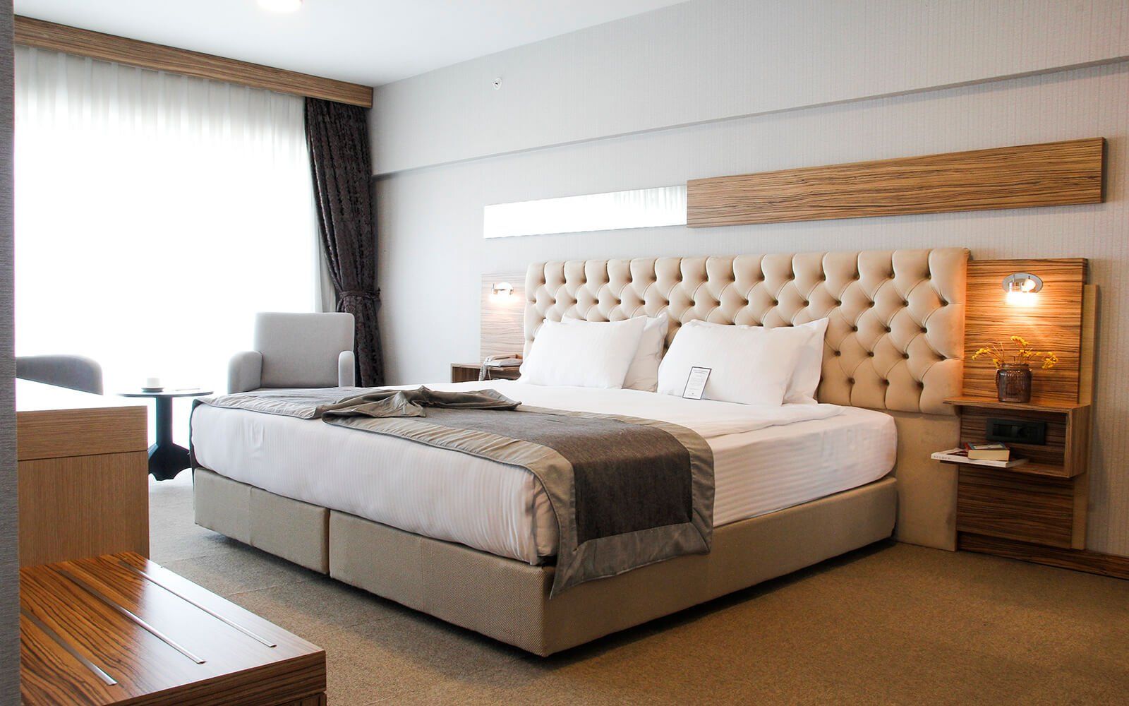 Kral yataklı ve sandalyeli bir otel odası.