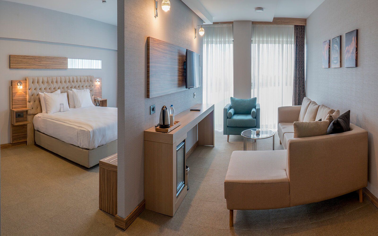 Yatak, kanepe, sandalye ve televizyonun bulunduğu bir otel odası.