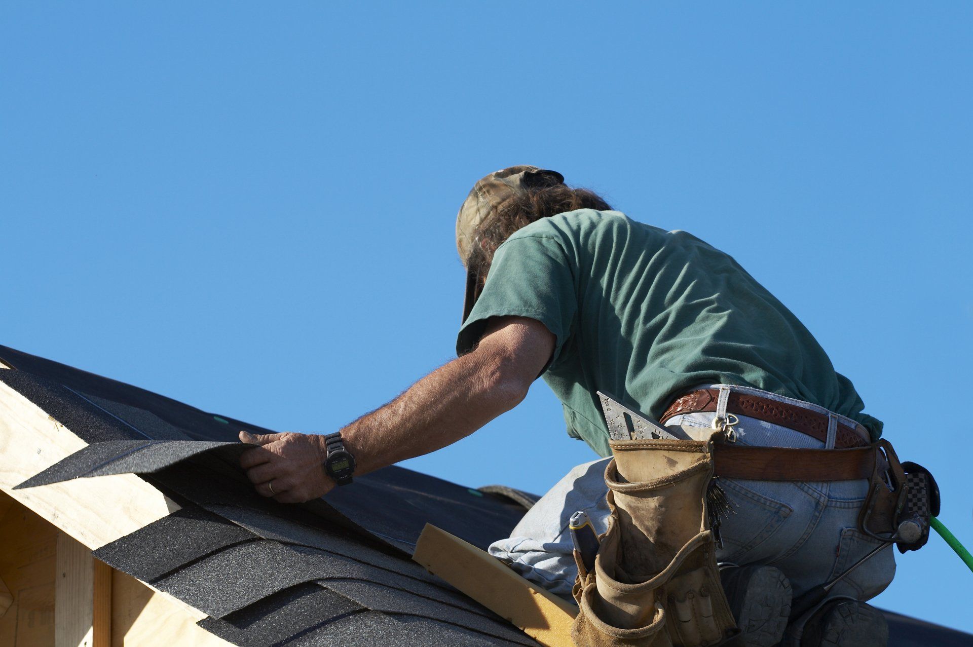 Roof Replacement — Man Covering The Roof With Flat Shingles in Columbus, OH