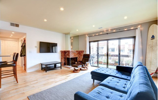 A living room with a blue couch and a surfboard on the wall