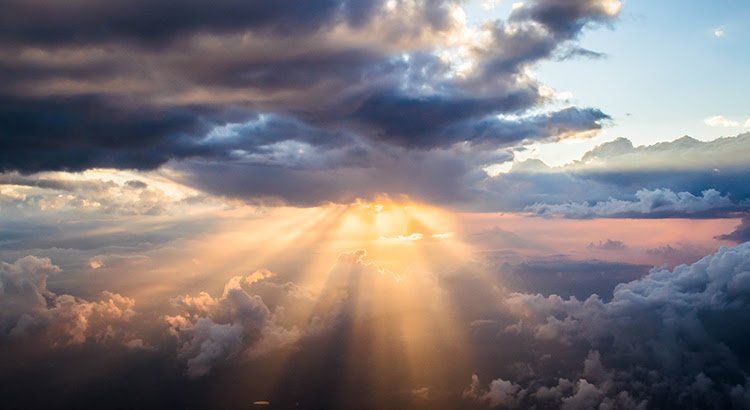 The sun is shining through the clouds in the sky.