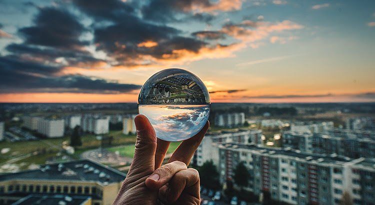 A person is holding a glass ball in their hand over a city.