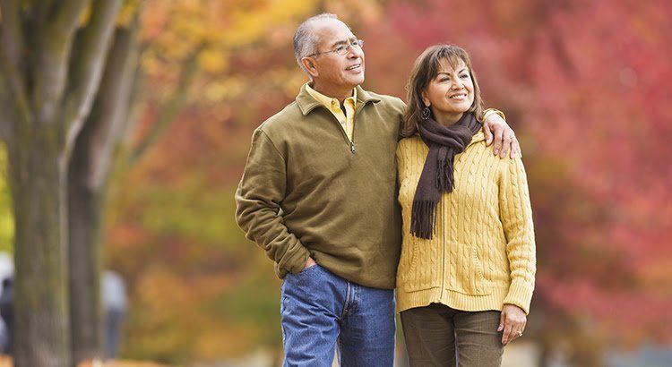 A man and a woman are standing next to each other in a park.