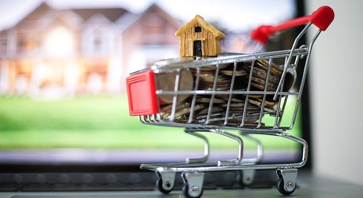 A shopping cart filled with coins and a small house.