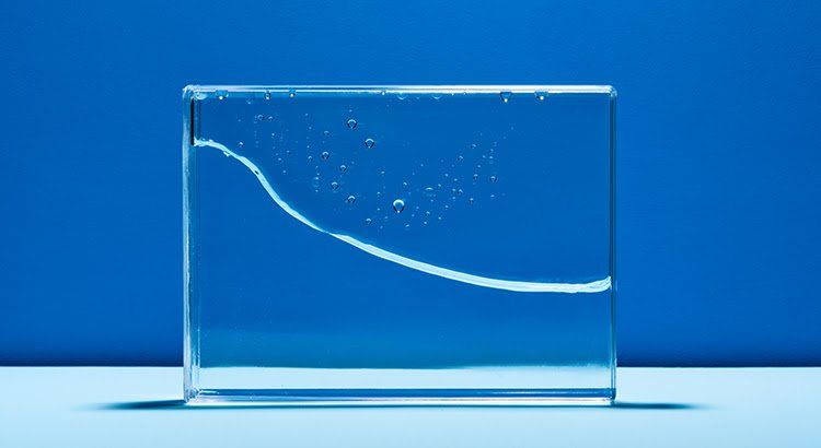 A glass block filled with water is sitting on a table.