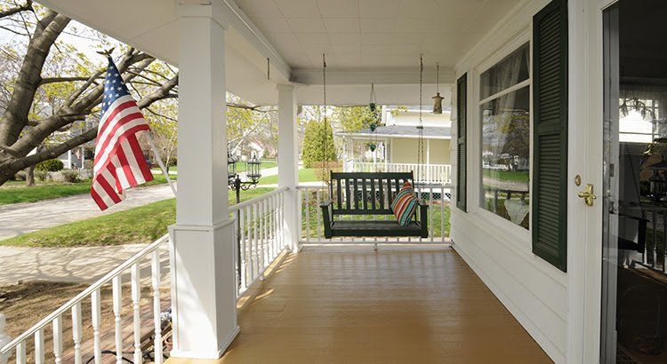 A porch with a swing and an american flag