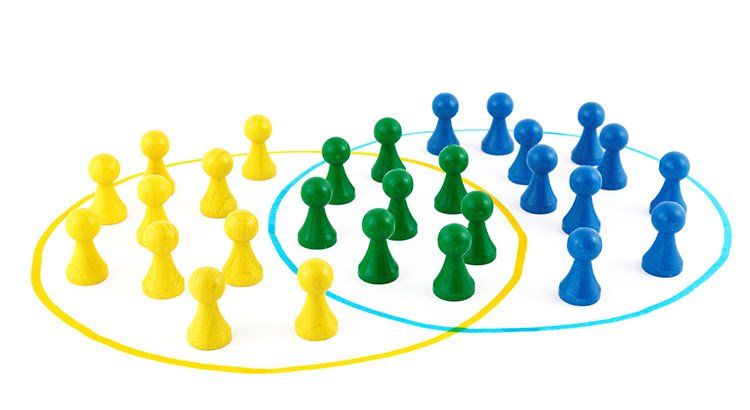 A group of yellow green and blue chess pieces are sitting in a circle.