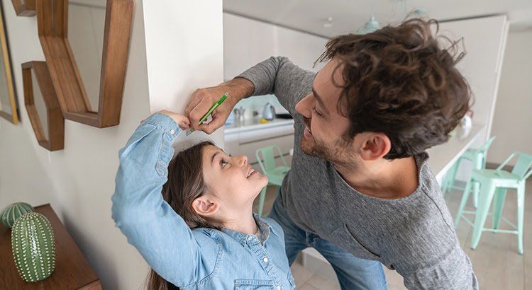 A man is measuring the height of a little girl.