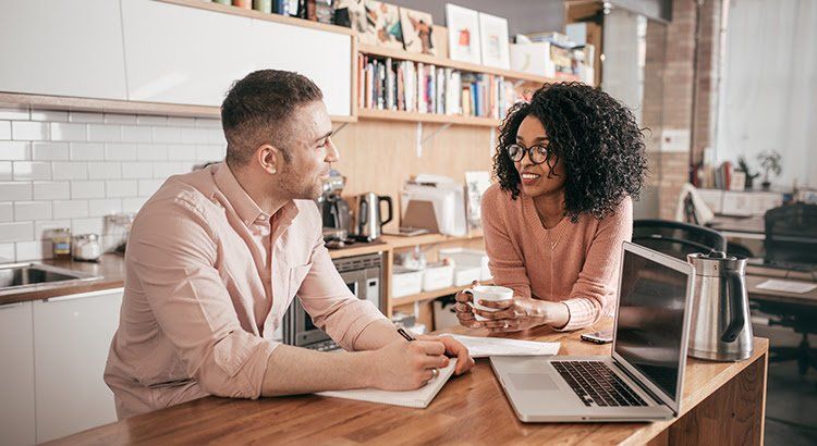 A man and a woman are sitting at a table with a laptop.