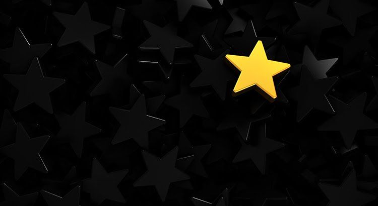 A yellow star is surrounded by black stars on a black background.