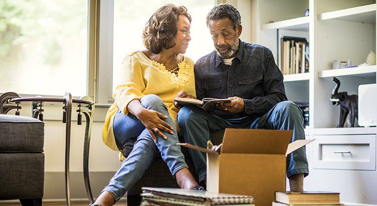 A man and a woman are sitting on a couch looking at a book.