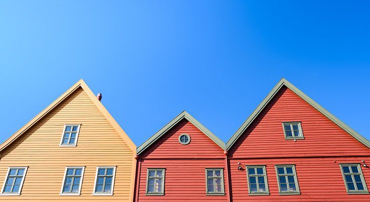 Three houses are lined up in a row against a blue sky.