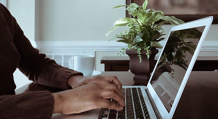 A person is typing on a laptop computer at a desk.