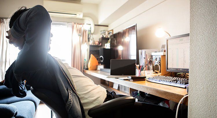 A man is sitting in a chair in front of a computer desk.