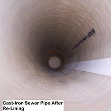 Interior view of a re-lined cast-iron sewer pipe, showing a smooth, clean surface from the inside.