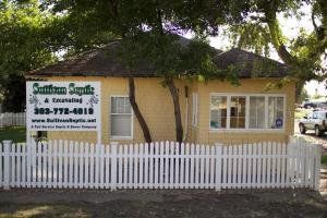 Yellow building with white picket fence; sign reads