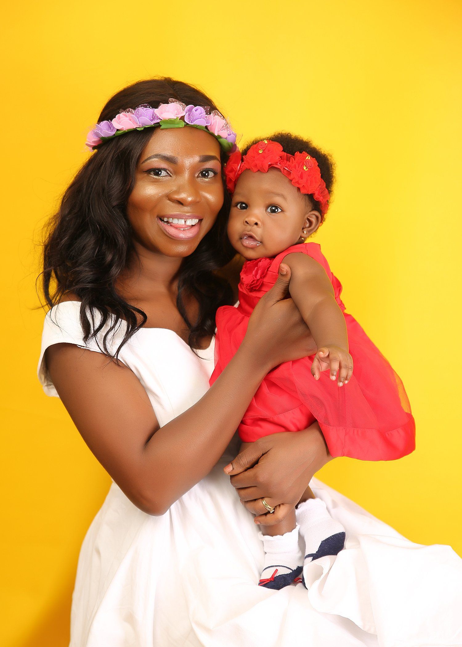 A woman in a white dress is holding a baby in her arms.