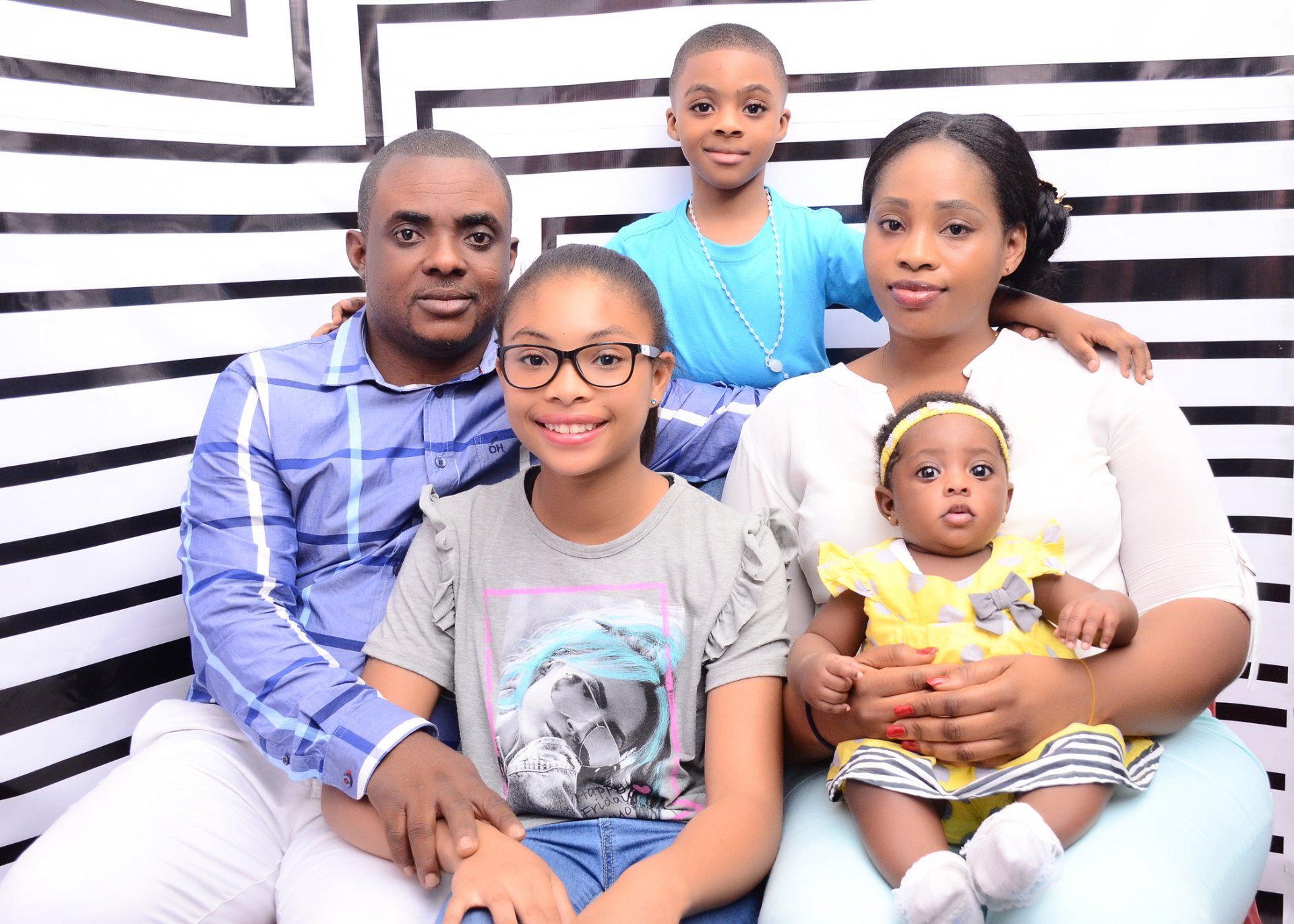 A family is posing for a picture in front of a striped wall.