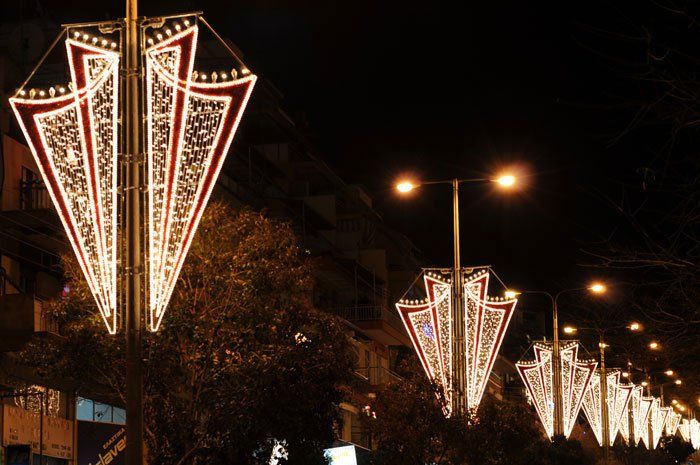 A row of street lights are lit up at night on a city street.