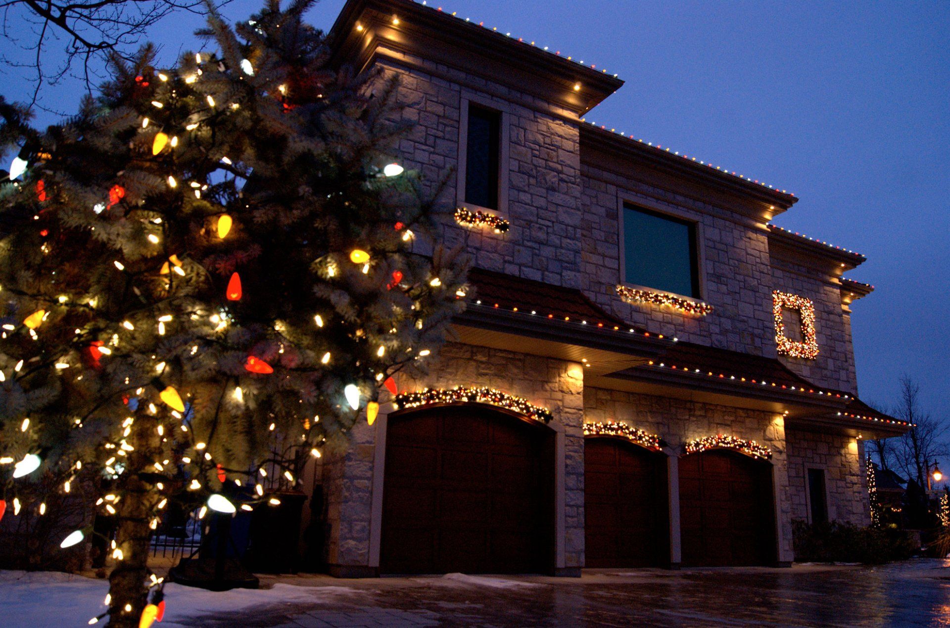A house decorated with christmas lights and a tree in front of it