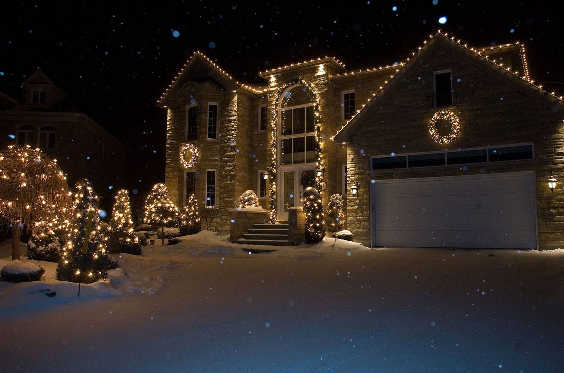A large house is decorated with christmas lights at night.