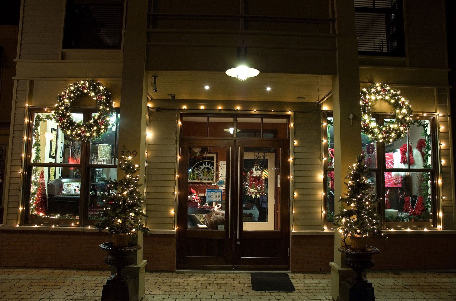 A store front decorated with christmas lights and wreaths