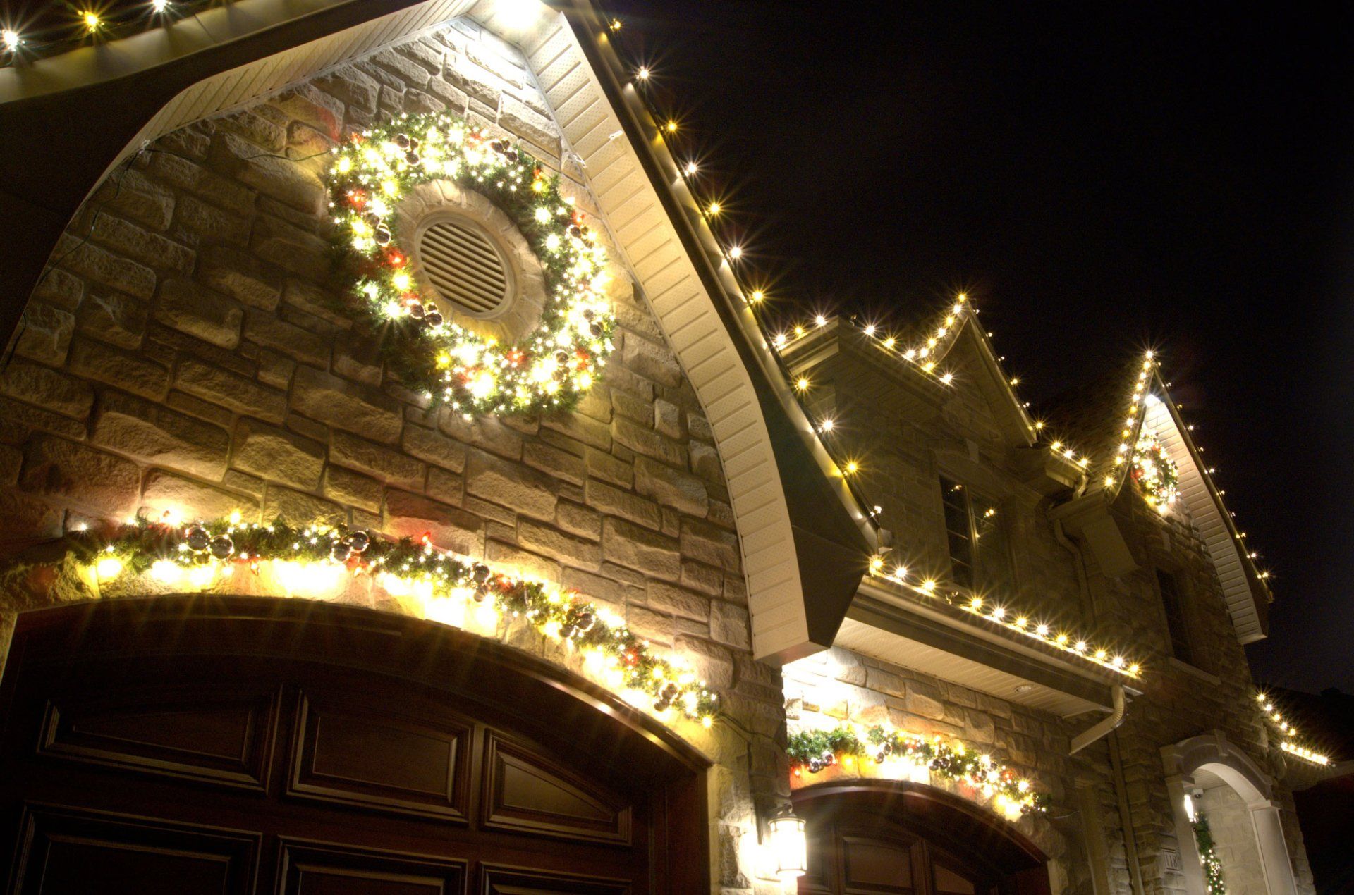 A house is decorated with christmas lights and a wreath.
