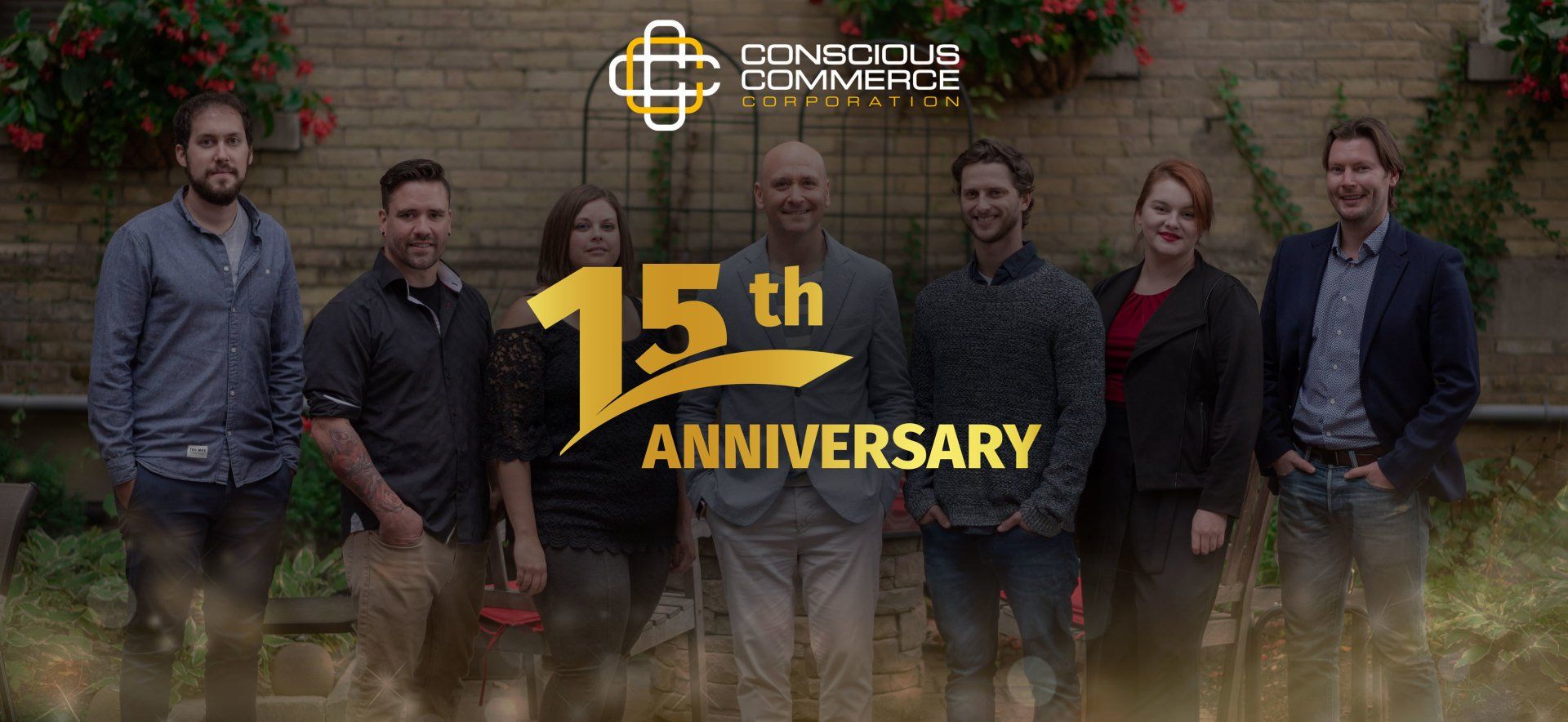 A group of people standing next to each other in front of a sign that says 15th anniversary.