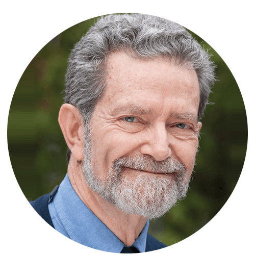 A man with gray hair and a beard is smiling in a circle.