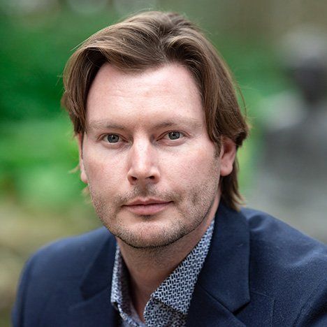A man in a suit and shirt is looking at the camera.