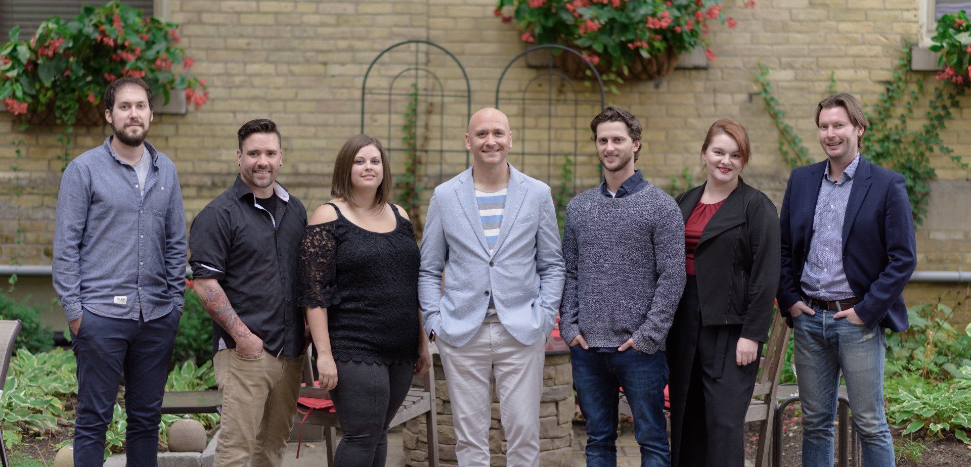 A group of people are posing for a picture in front of a brick wall.