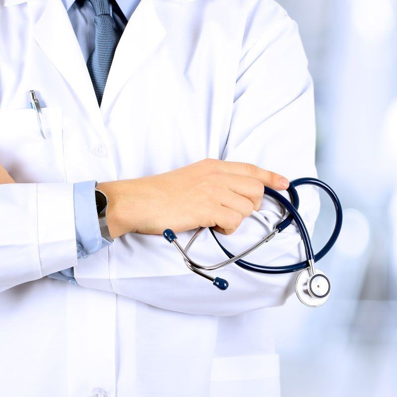 Doctor in a white coat holding a stethoscope across folded arms