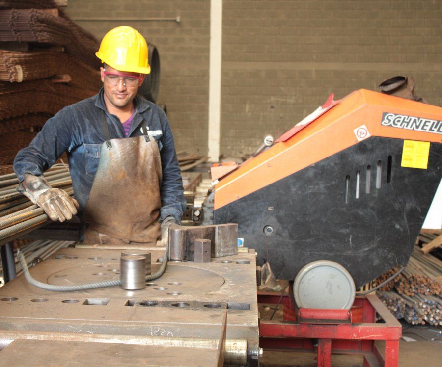 Hombre realizando forma en hierro con maquina