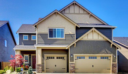 a large house with two garage doors and a blue sky in the background