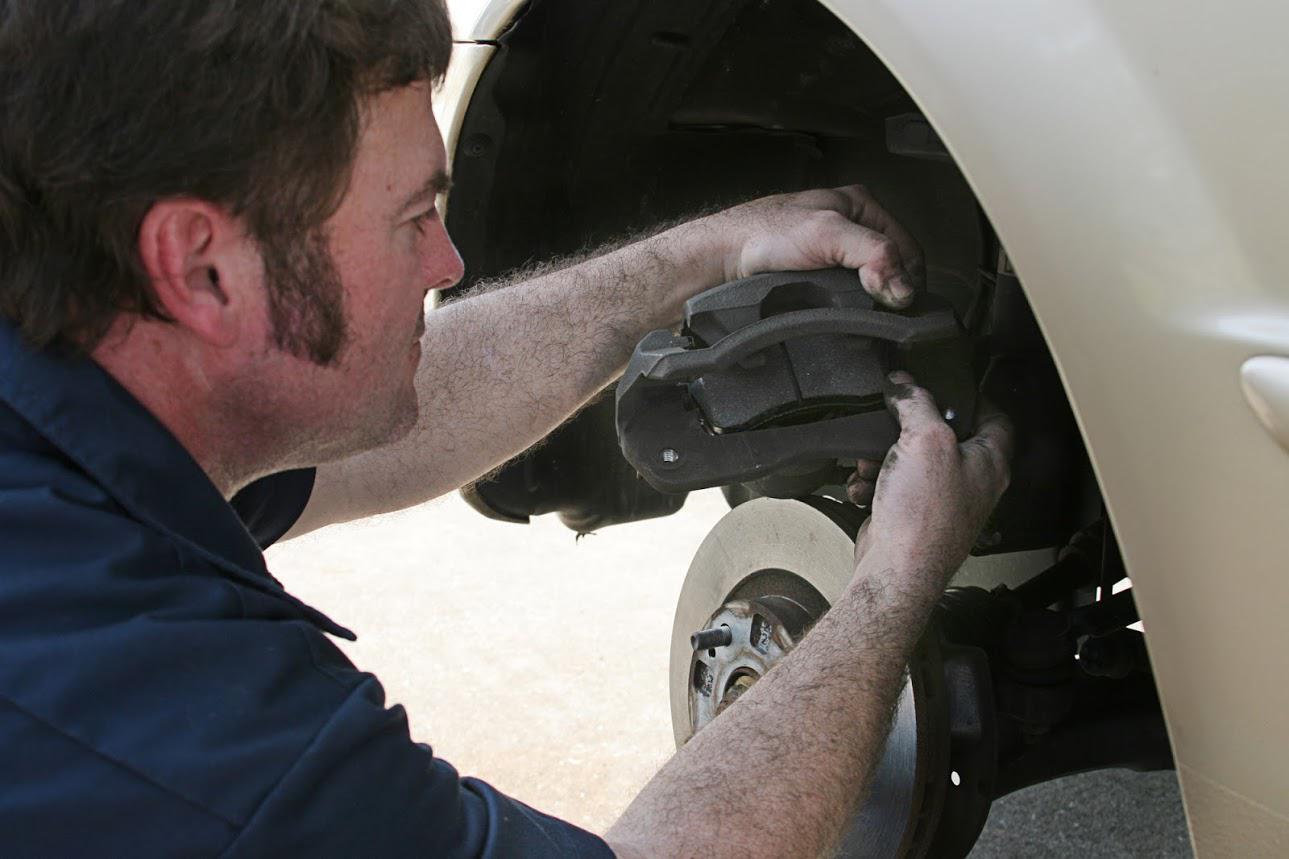 A man in a blue shirt is working on a car