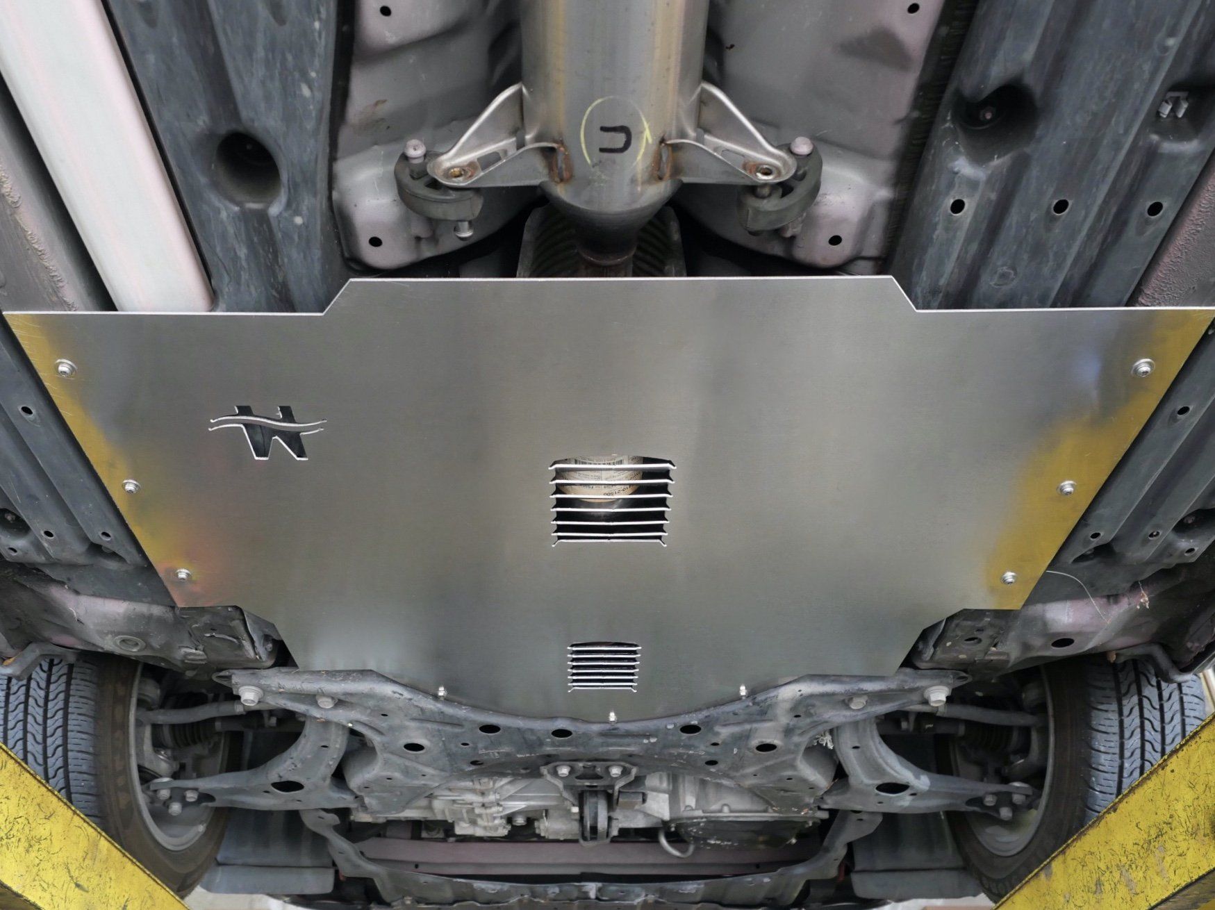 The underside of a car with a metal plate on it.