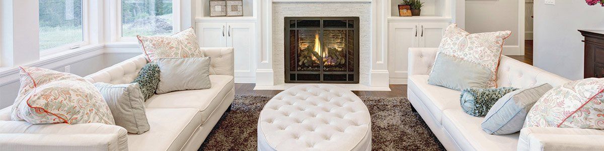 Bright living room with two sofas, patterned pillows, and a fireplace centered on the far wall