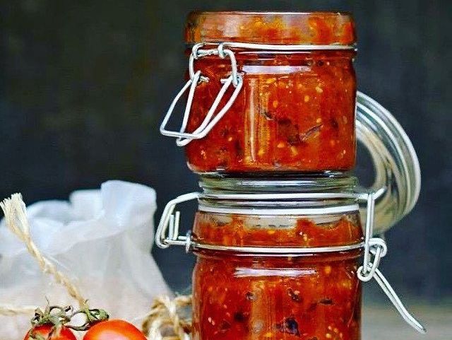 Two jars of tomato sauce are stacked on top of each other on a table.