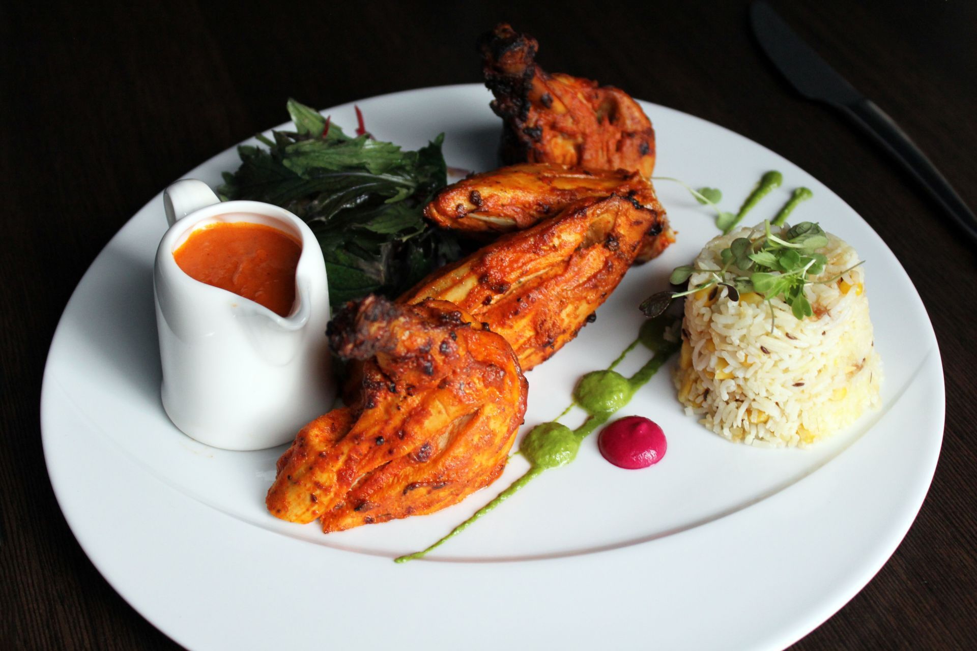 A white plate topped with chicken and rice on a table.
