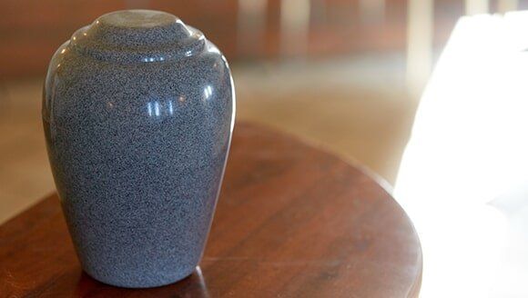 Urn, Candle And A Picture Frame On A Table — Quality Cremation Services in Rockhampton, QLD